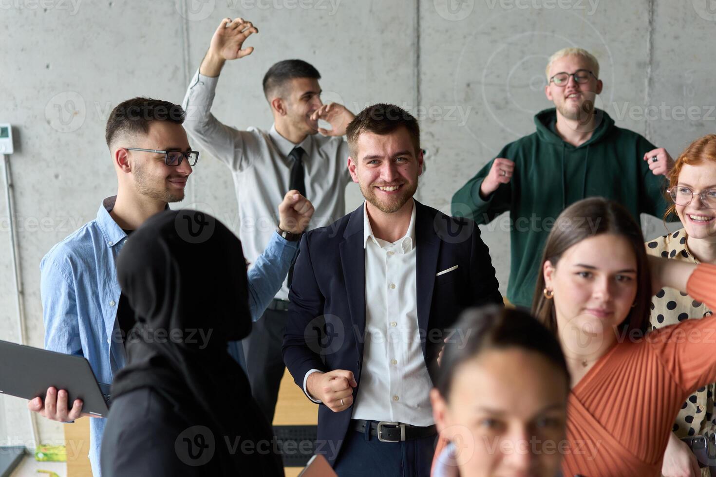 A diverse team of business professionals ecstatically celebrating their success in a modern office, expressing triumph and unity after achieving their goals photo
