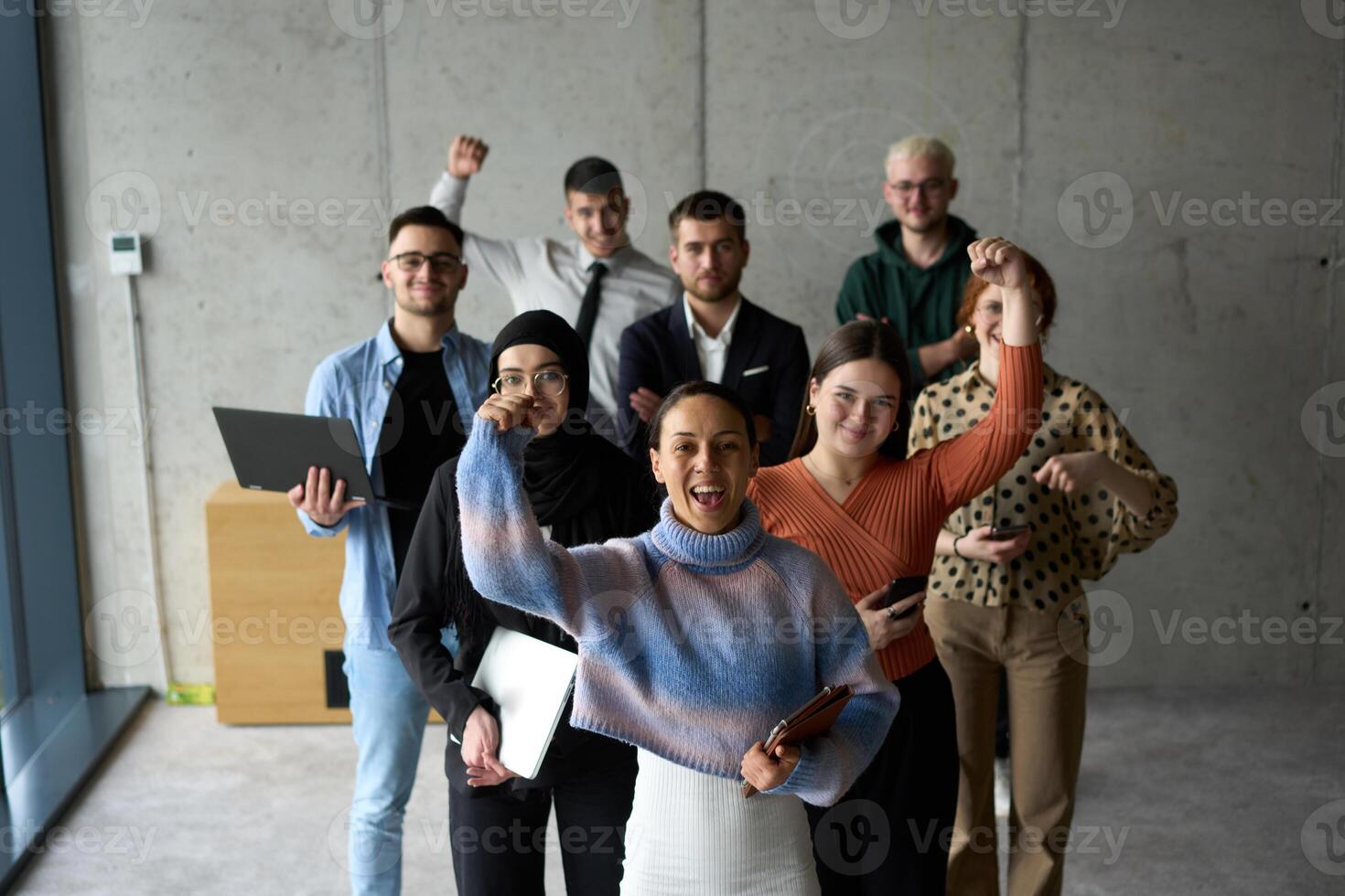 A diverse team of business professionals ecstatically celebrating their success in a modern office, expressing triumph and unity after achieving their goals photo