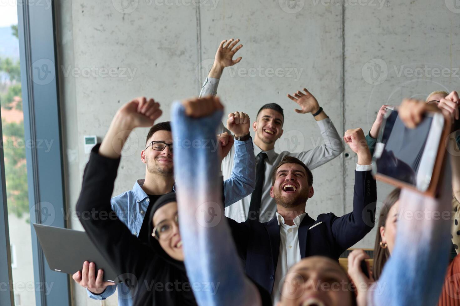 A diverse team of business professionals ecstatically celebrating their success in a modern office, expressing triumph and unity after achieving their goals photo