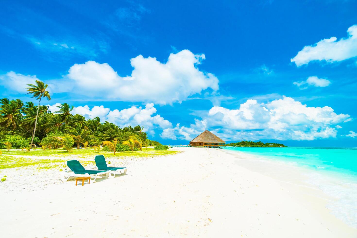 A beach with two lounge chairs and a hut photo
