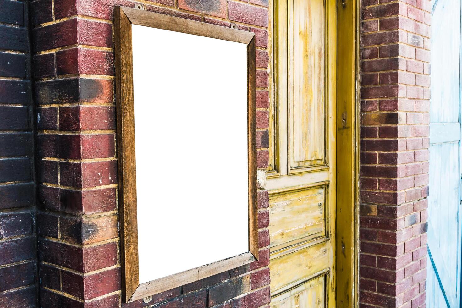 A blank white sign is hanging on a brick wall photo
