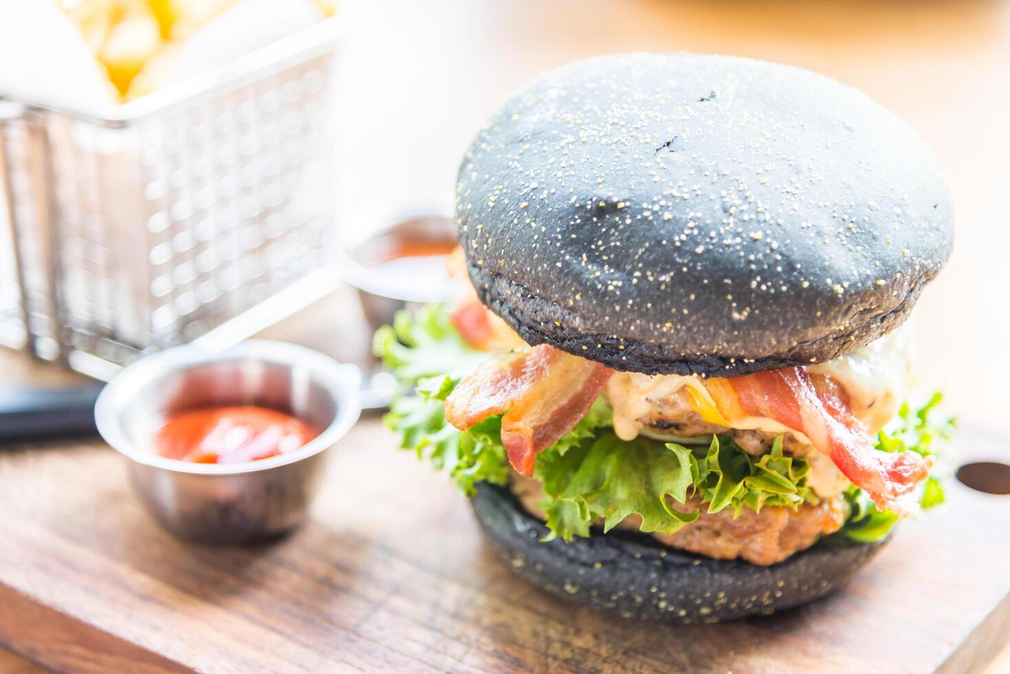 A burger with a black bun sitting on a cutting board photo
