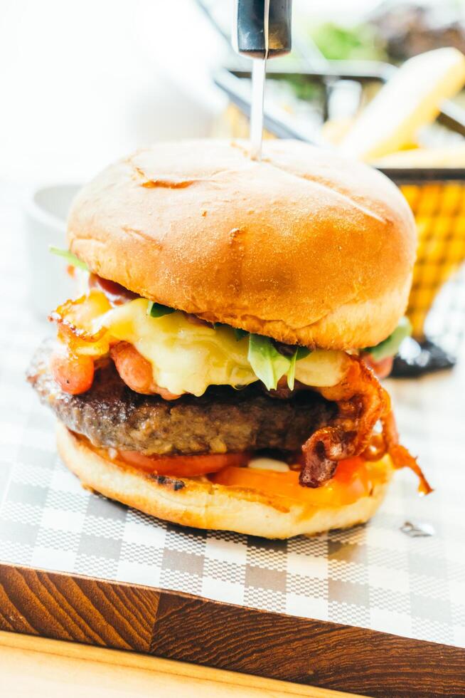 A burger with cheese and bacon on a wooden cutting board photo