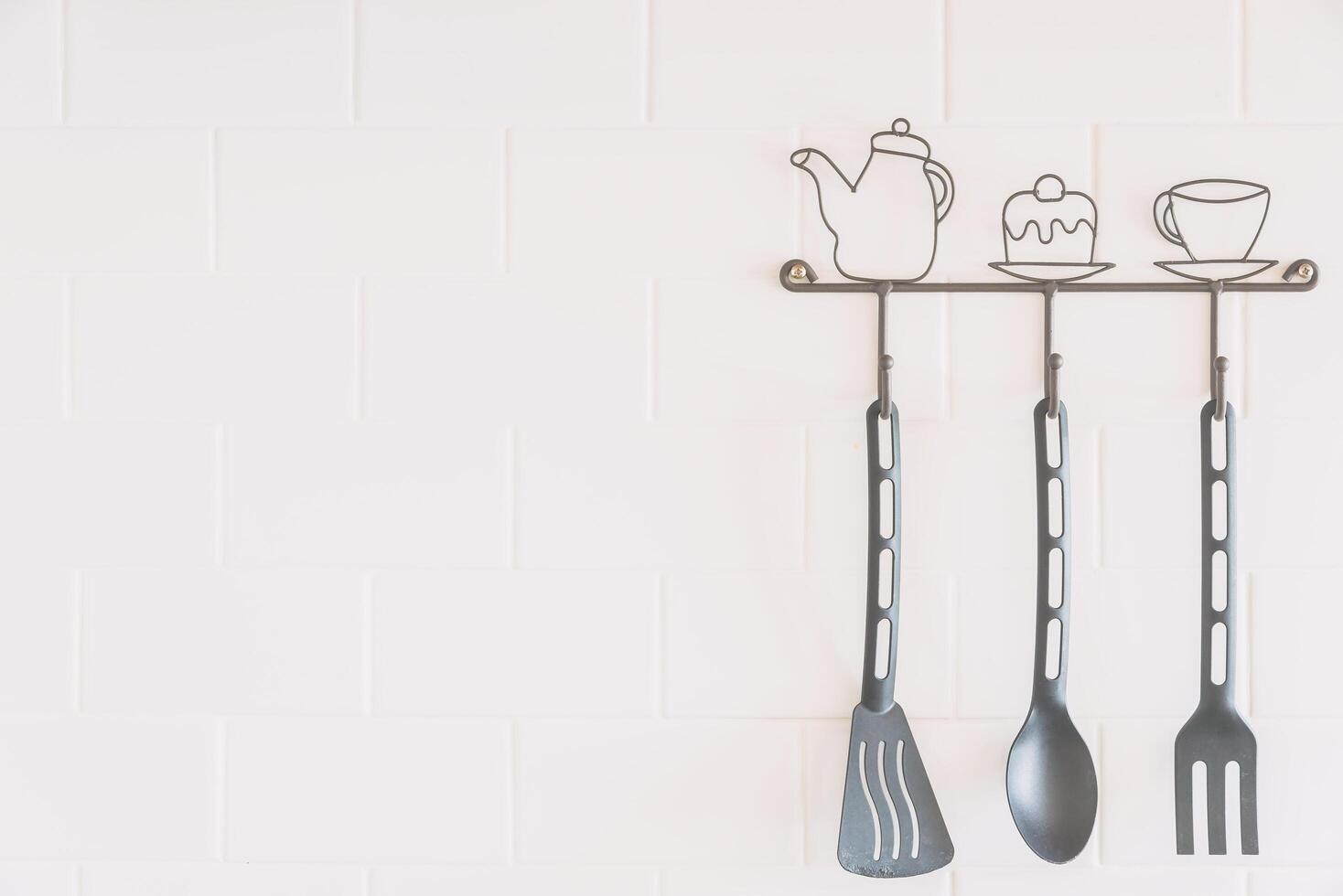 A kitchen utensil rack with three spoons and a fork photo