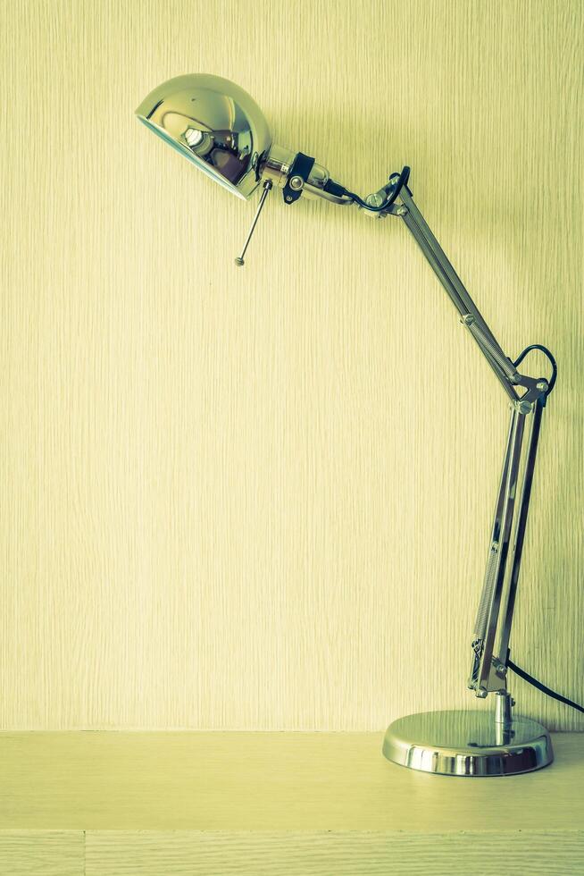 A lamp on a desk in front of a wall photo