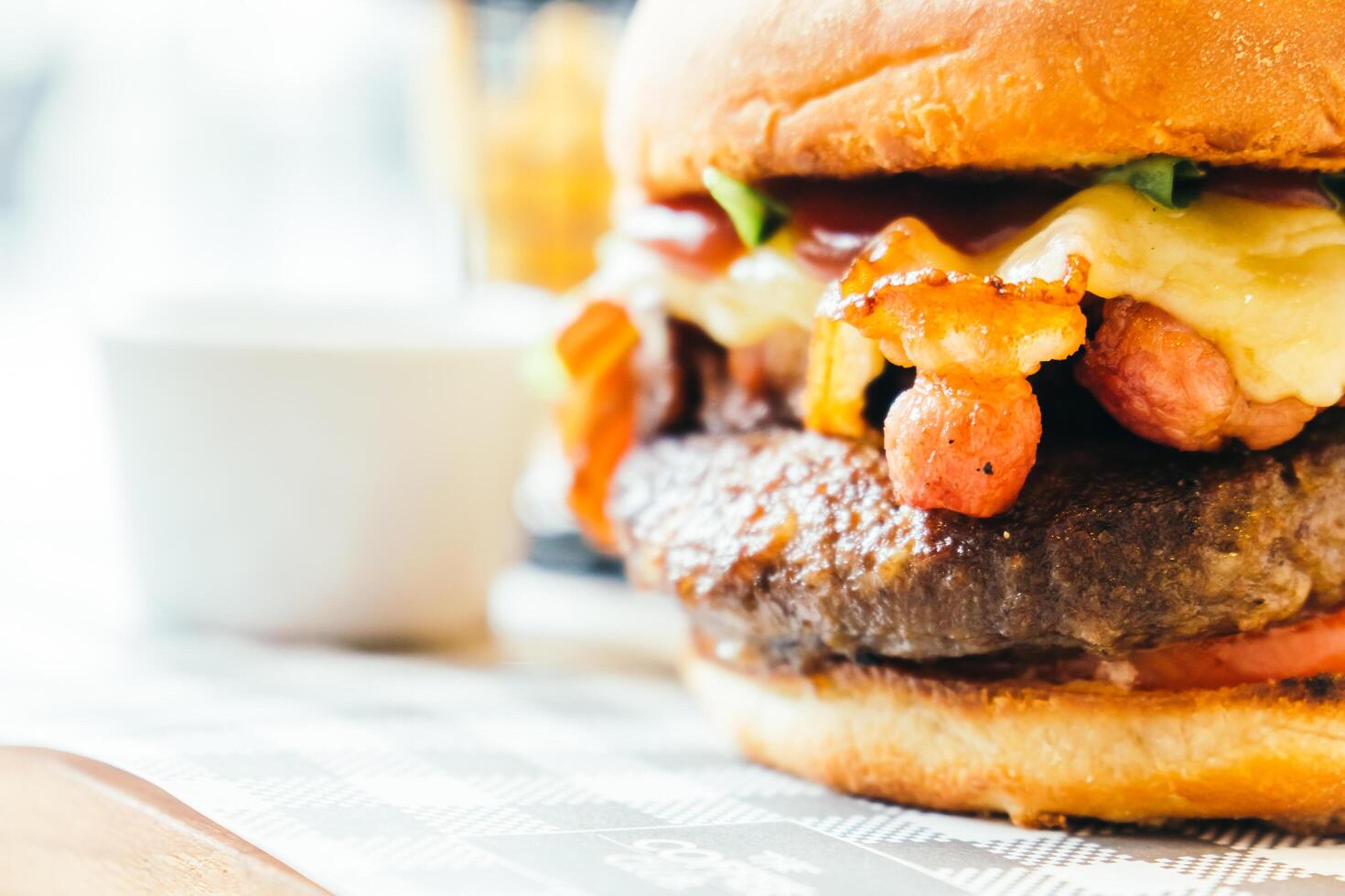 A large hamburger with cheese and bacon sitting on a table photo