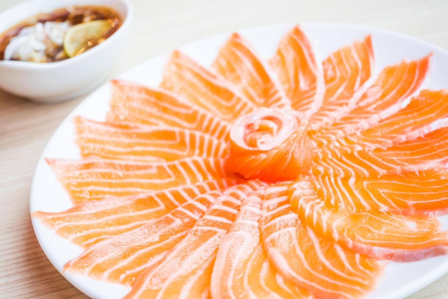 A plate of salmon on a table with a bowl of sauce photo