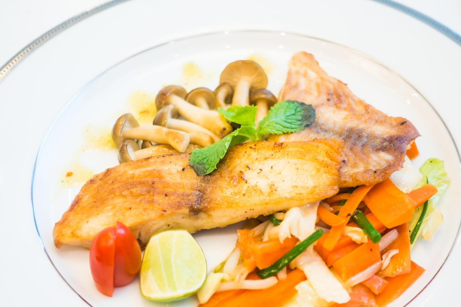 A plate of food with vegetables and a piece of fish photo