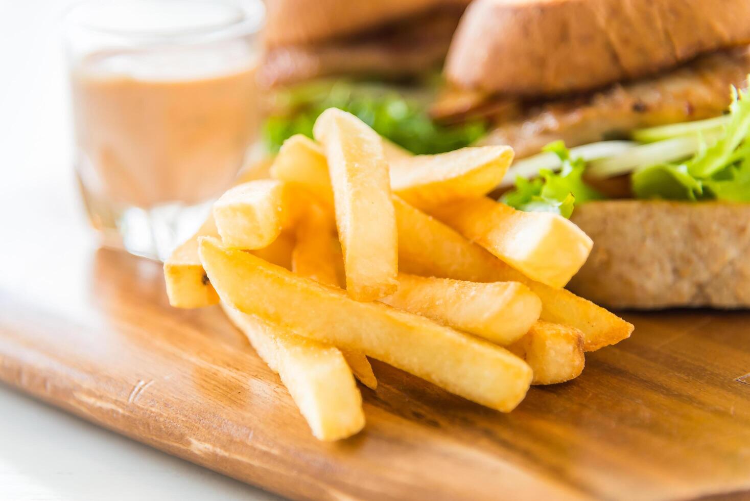 A sandwich and french fries on a wooden cutting board photo