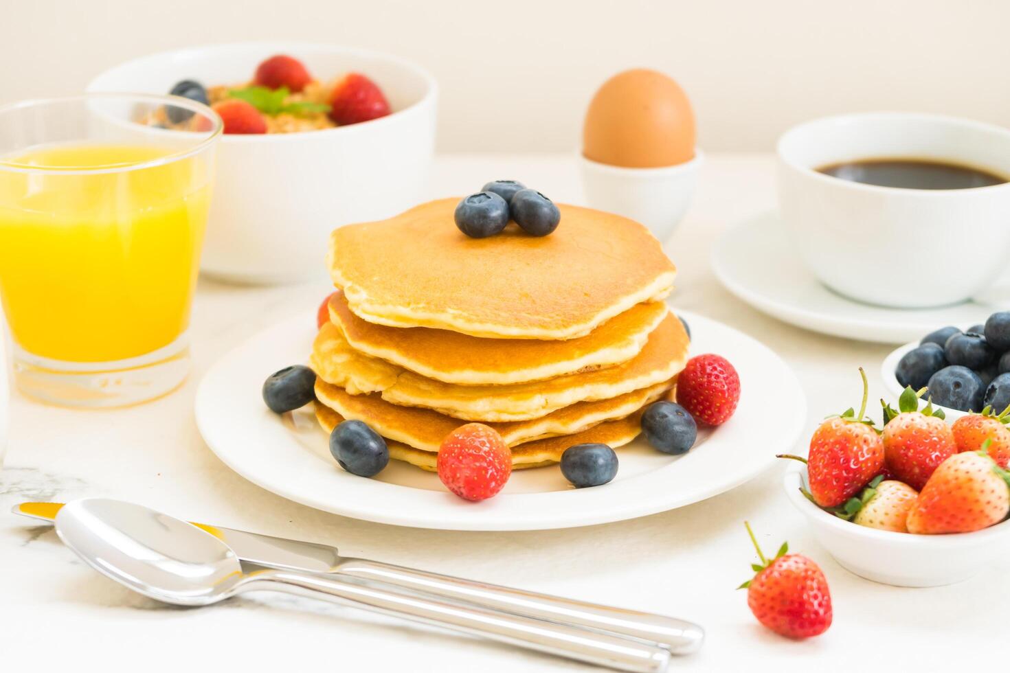 A stack of pancakes with berries and orange juice photo