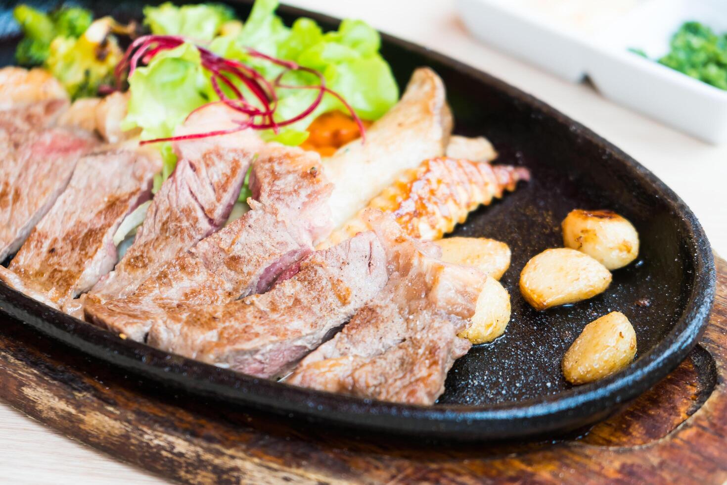 A steak on a black plate with potatoes and vegetables photo
