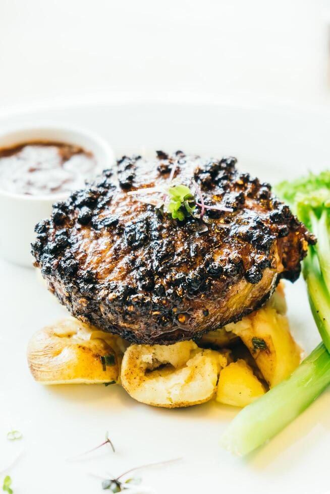 A steak with vegetables and sauce on a white plate photo
