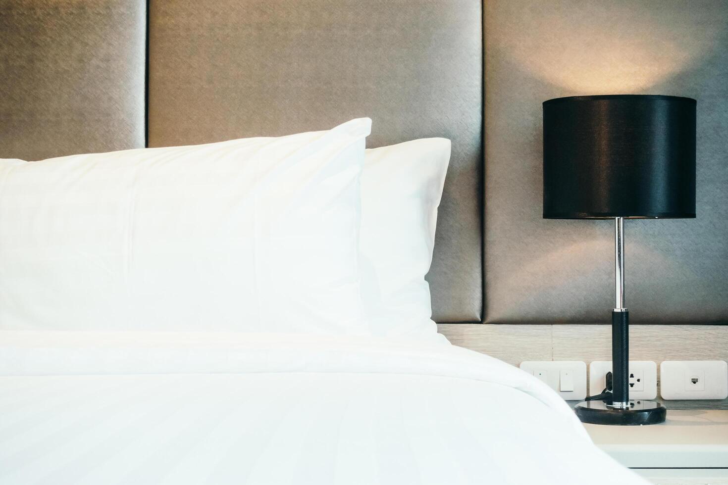A white bed with a black lamp on top photo