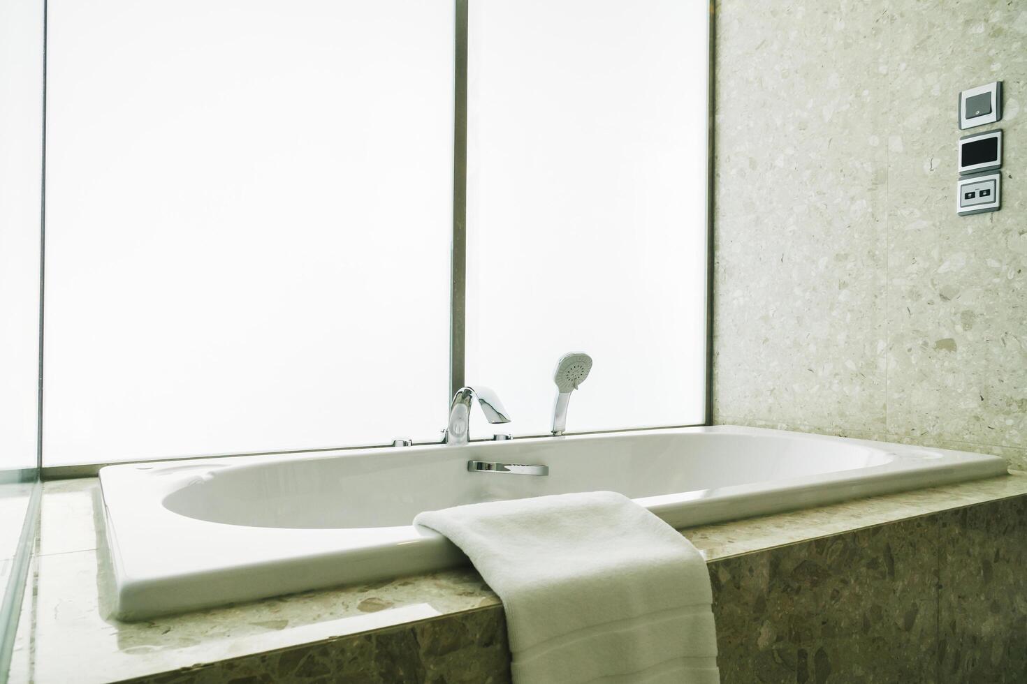 A white bathtub sitting in a bathroom next to a window photo