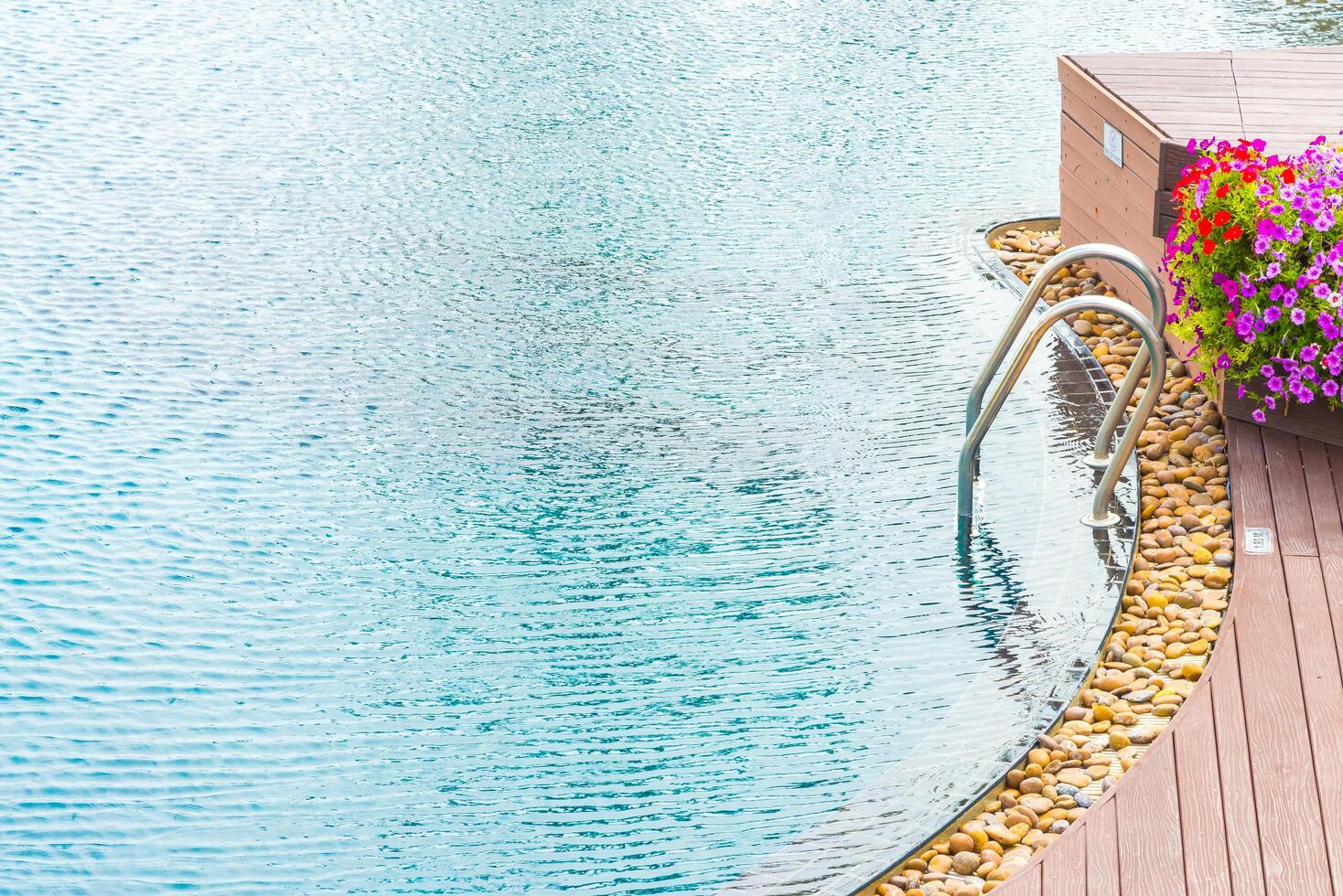 A wooden deck with a pool and a flower pot photo