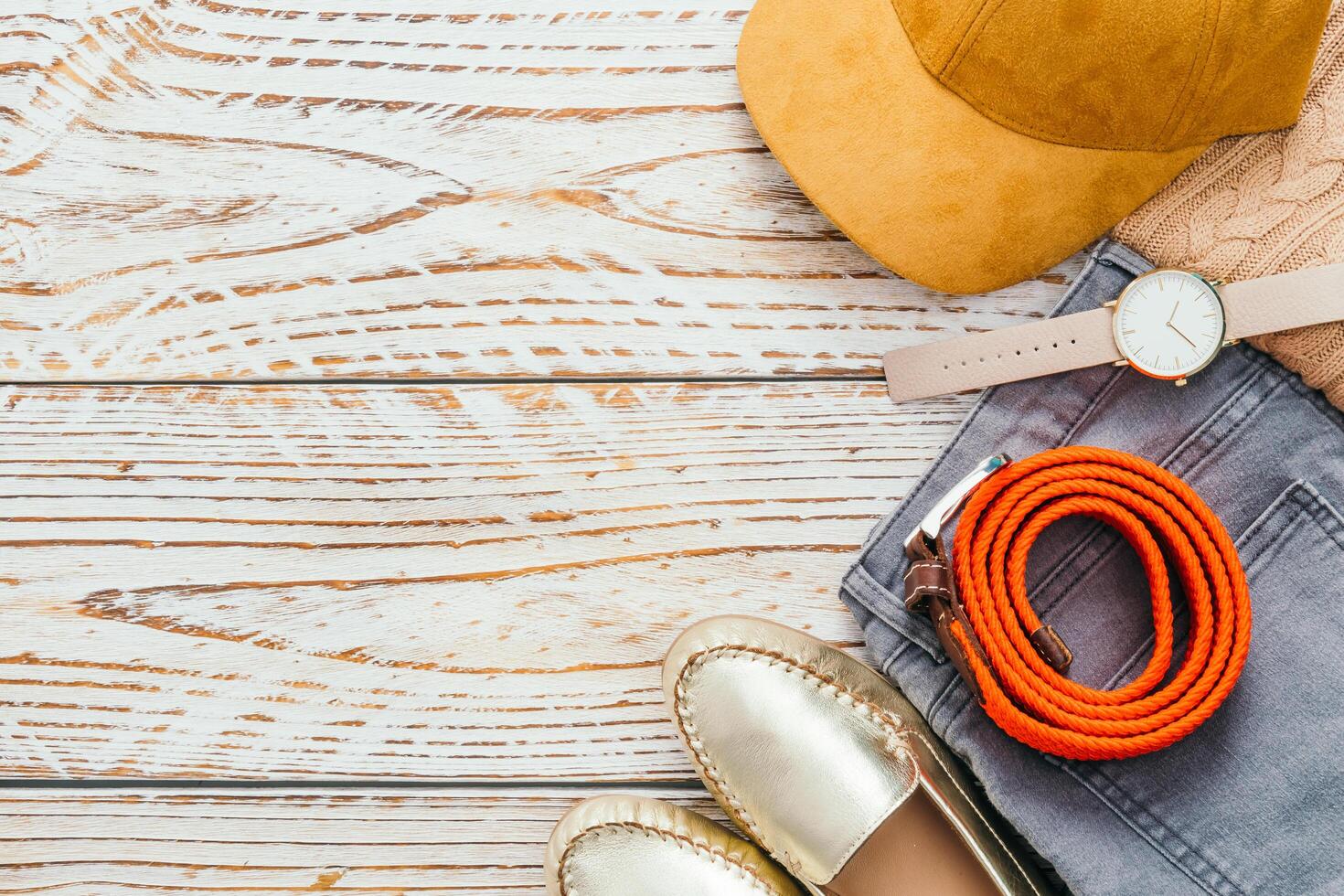 A woman's shoes, hat, watch, and other accessories on a wooden table photo