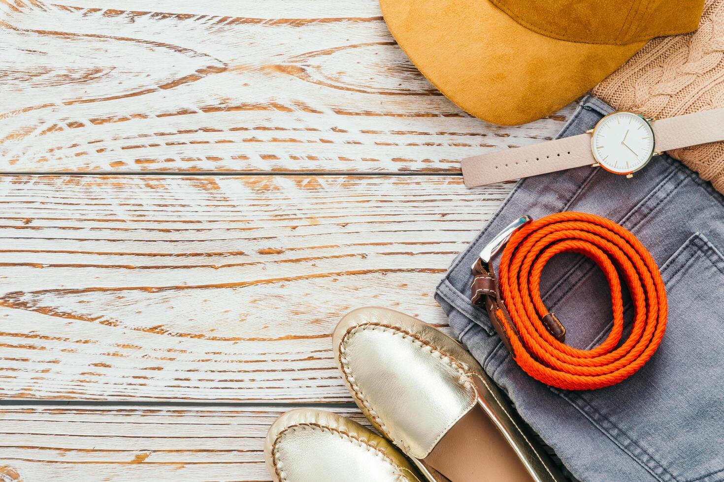 A woman's shoes, hat, watch, and other accessories on a wooden table photo