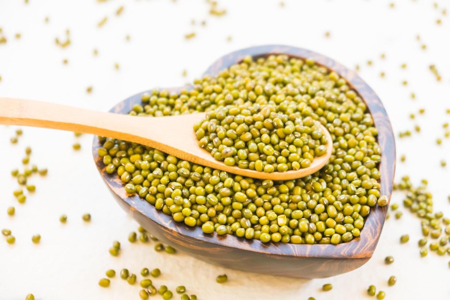 Green peas in a wooden spoon on a white background photo