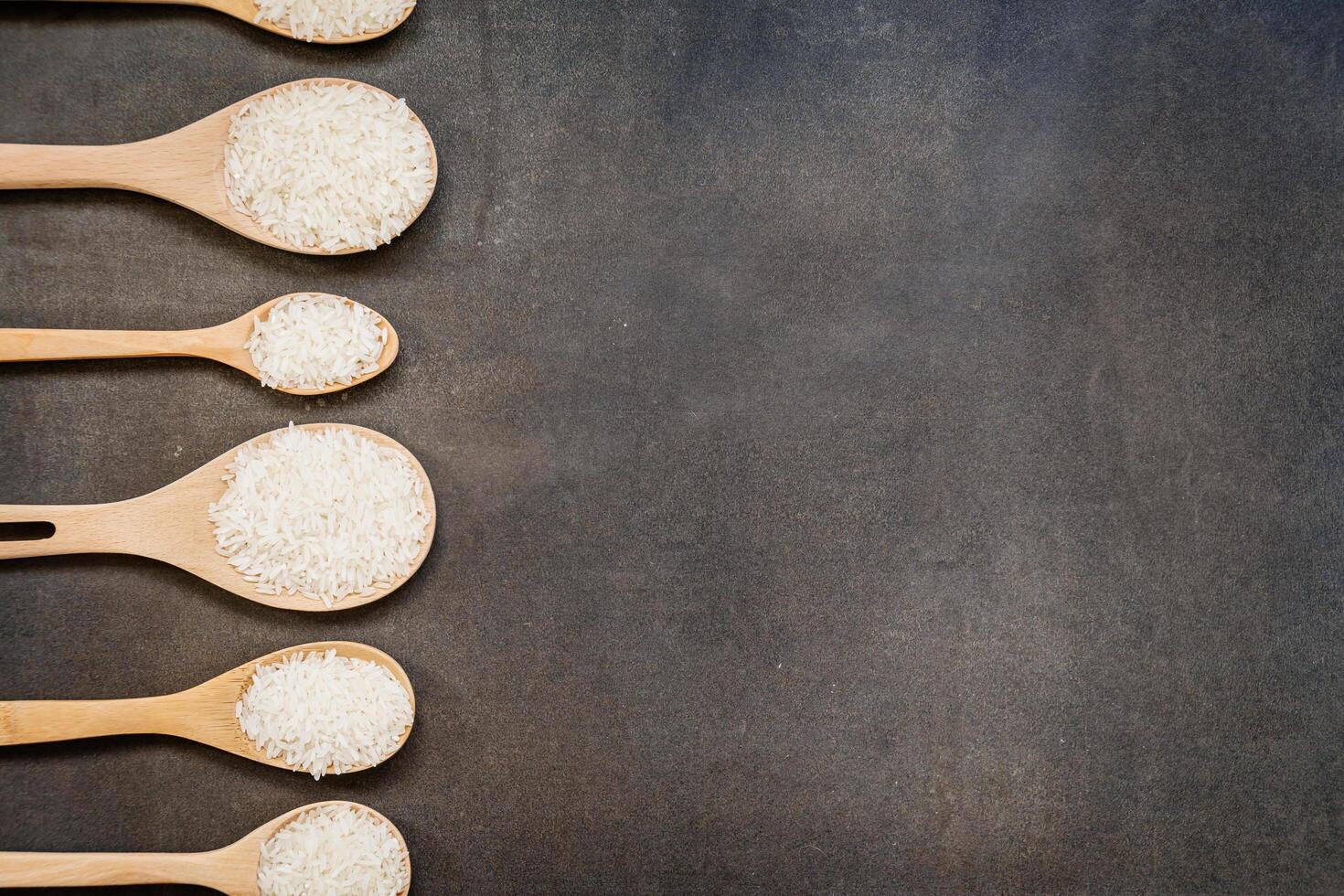 Six wooden spoons with rice in them on a black background photo