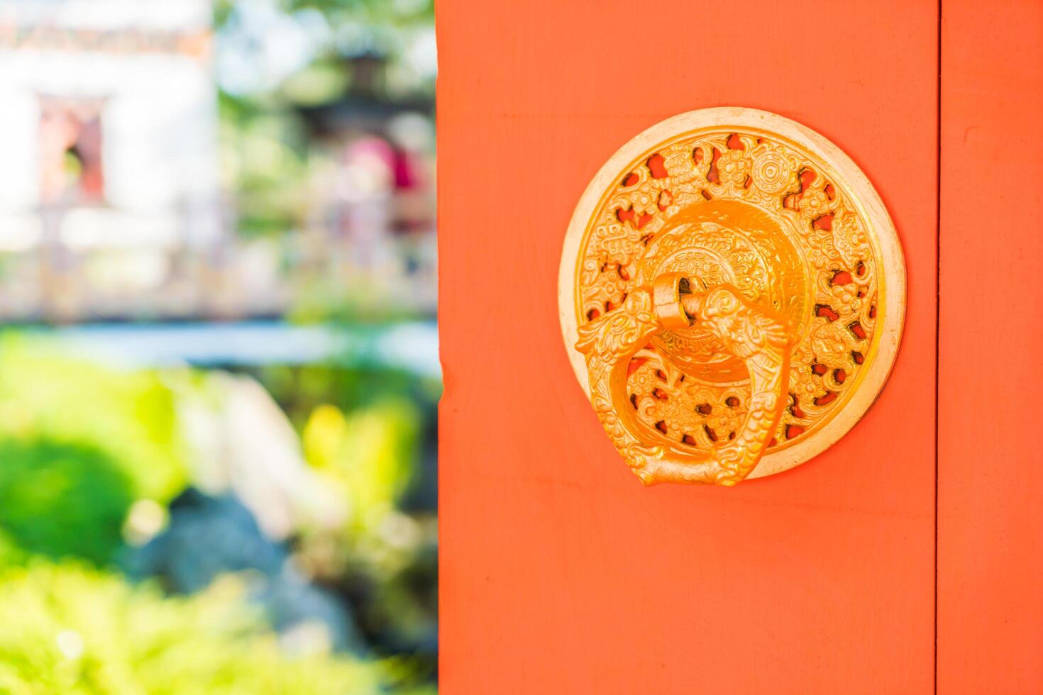 A golden door knocker on an orange door photo