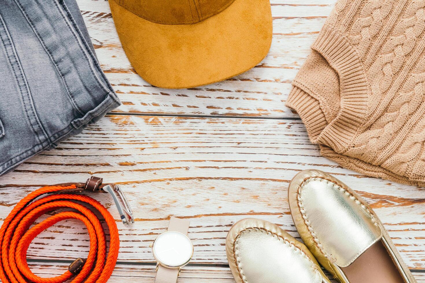 A hat, shoes, and a purse are on a wooden table photo