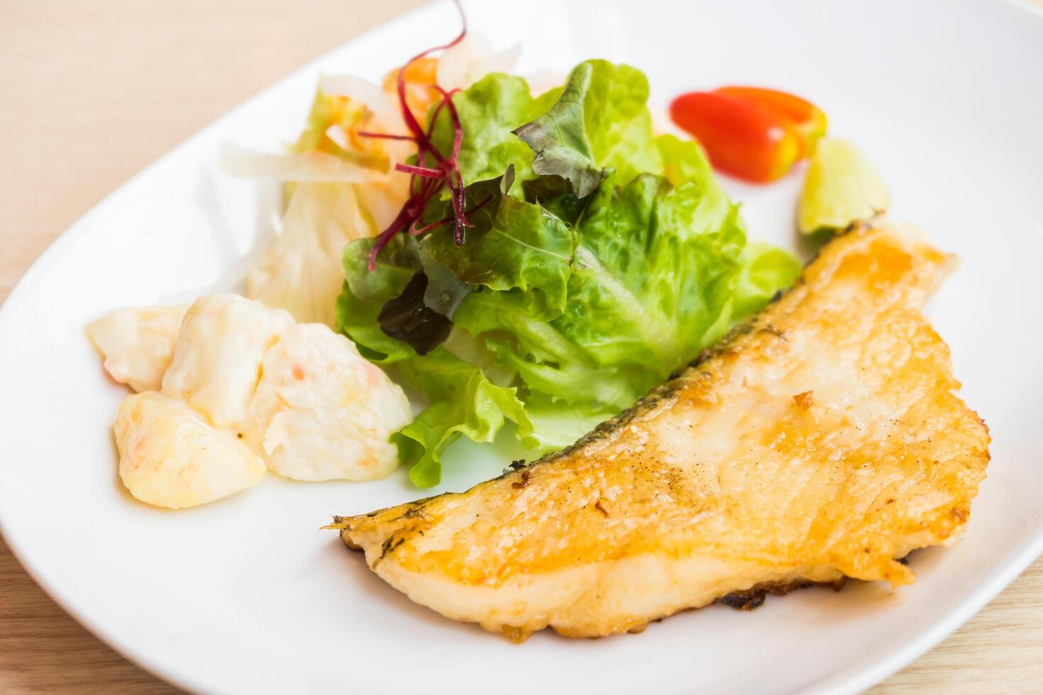 A plate with a fish and salad on it photo