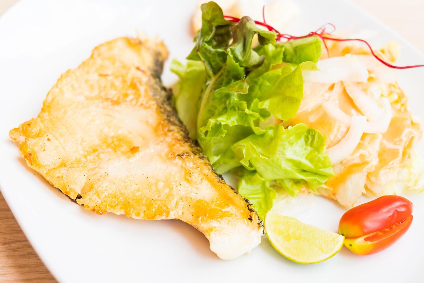 A white plate topped with fish and vegetables photo