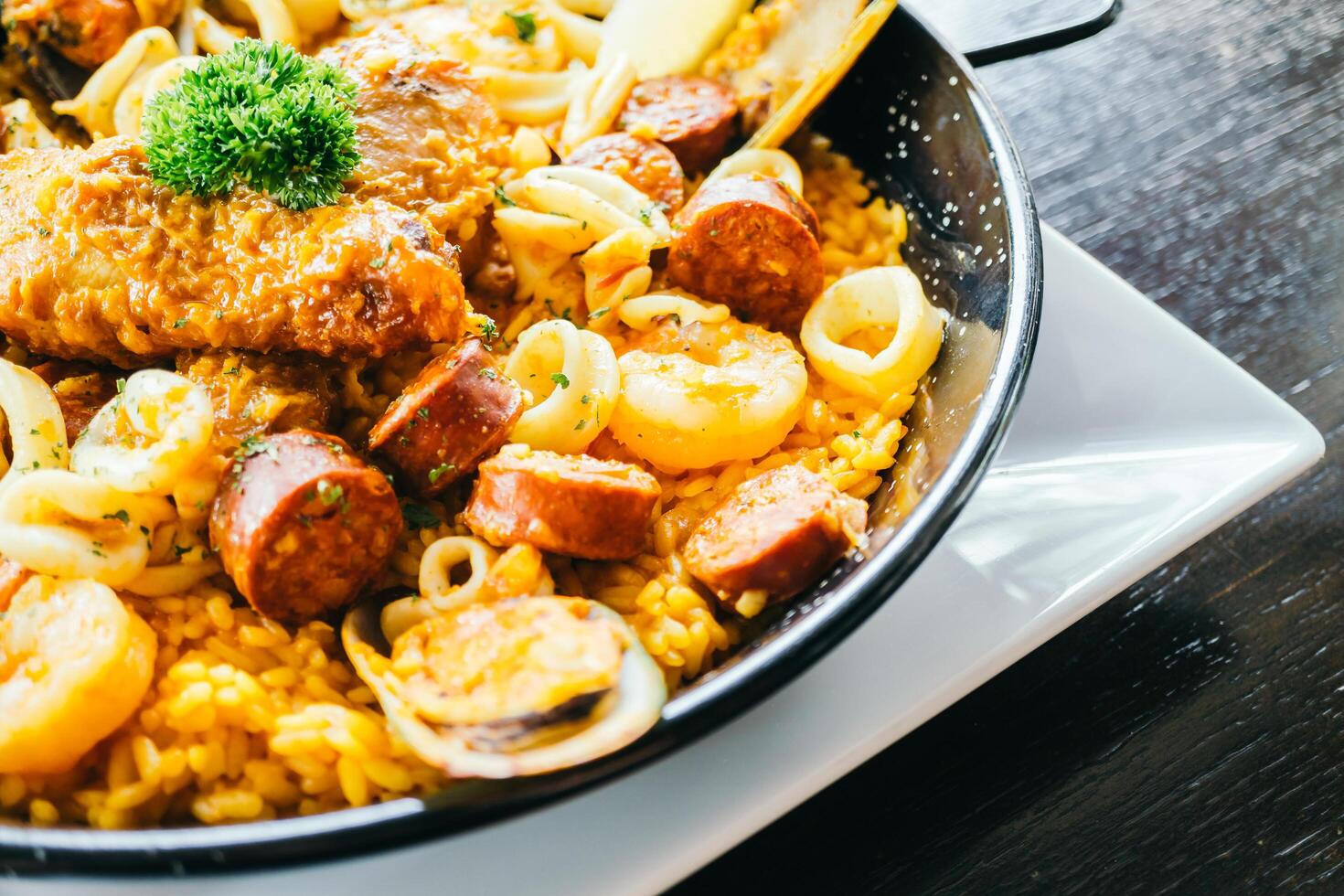 A pan with rice, meat and seafood on top photo