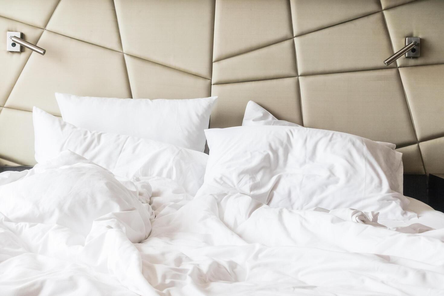 An unmade bed with white sheets and pillows photo