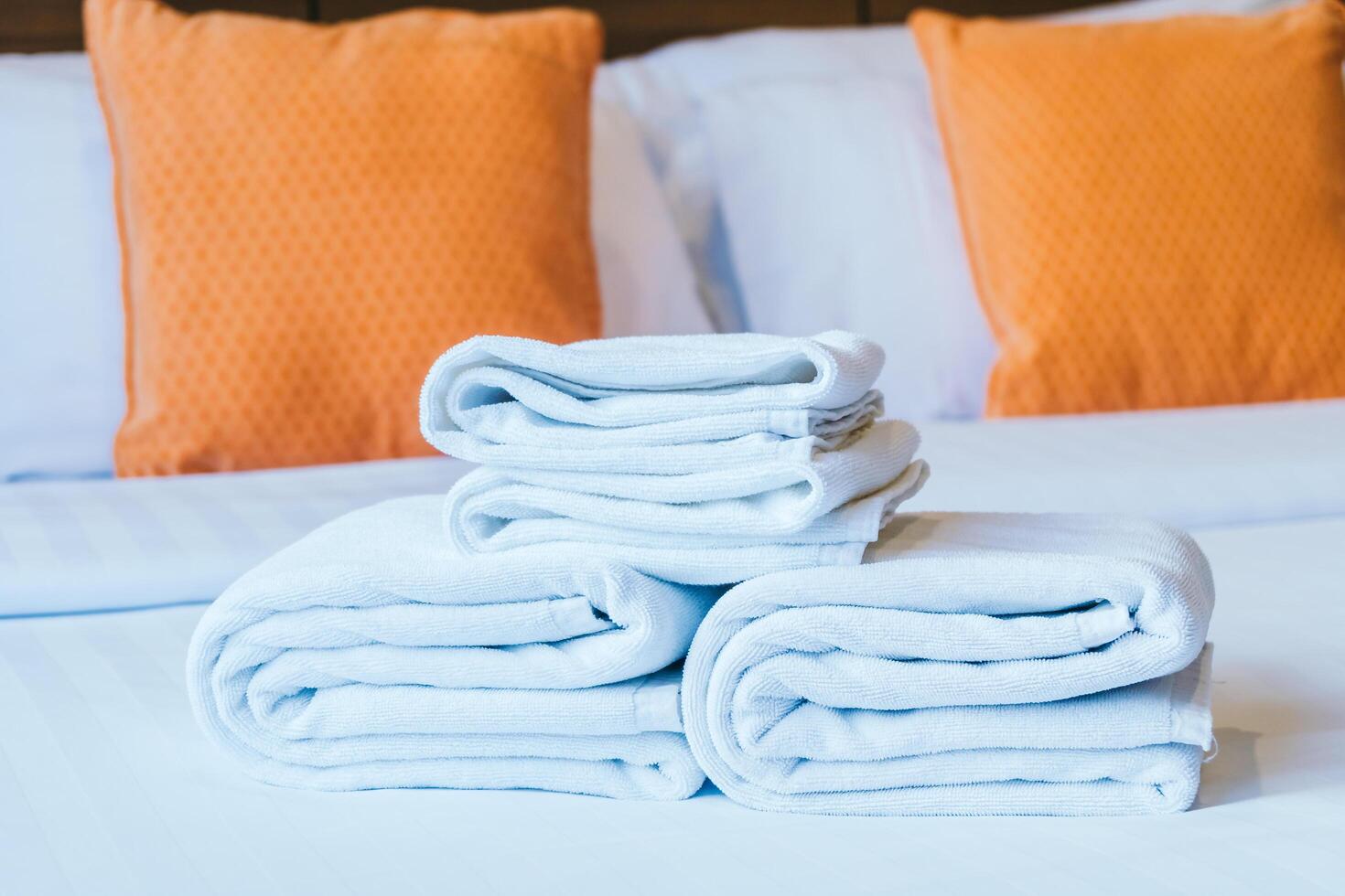 Towels on a bed with orange pillows photo