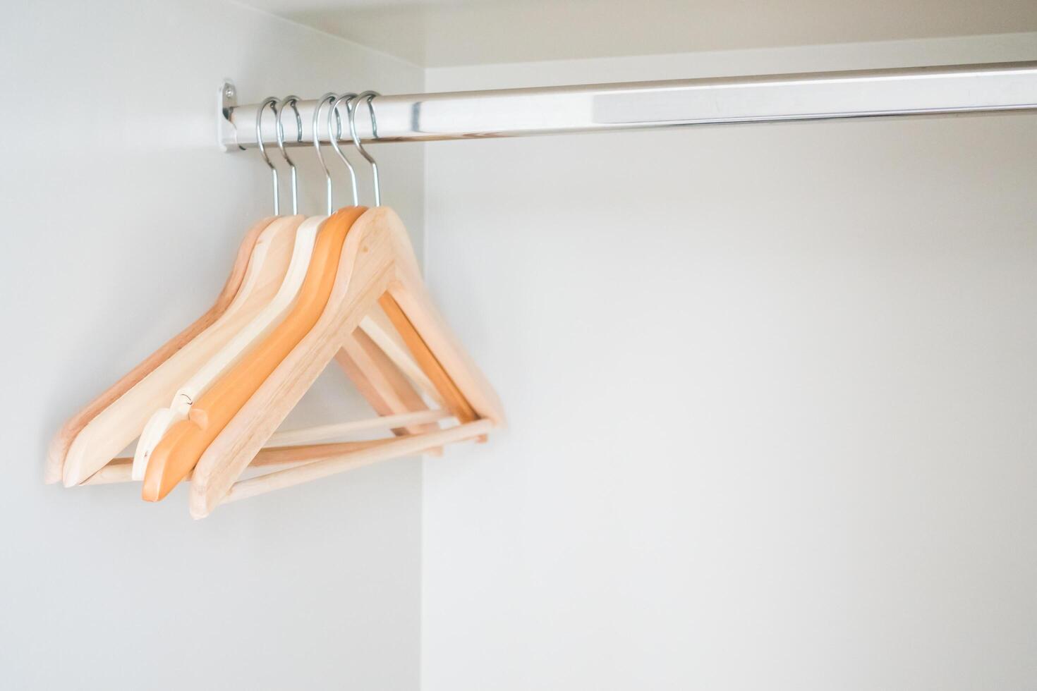 A wooden hanger hangs on a white wall photo