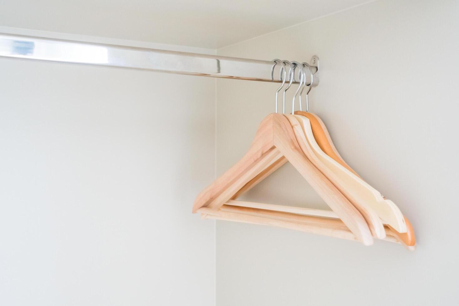 A wooden hanger hangs on a white wall photo