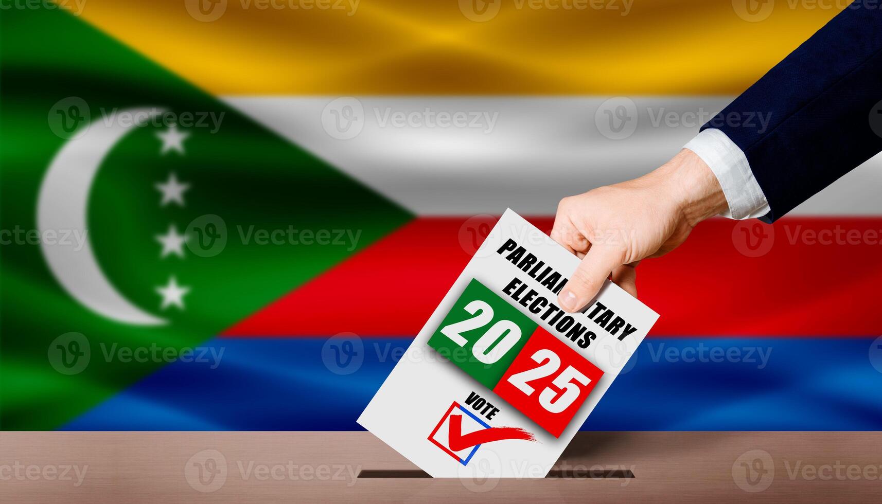 Hand holding ballot in voting ballot box with Comoran flag in background. Comoran parliamentary elections photo