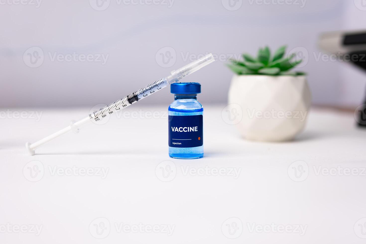 blue vaccine with syringe on top of it on a white table. health and medical concept photo
