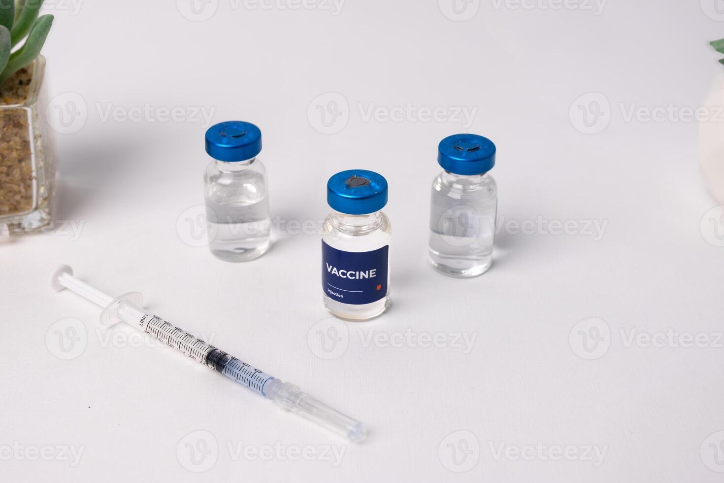 top view of some vaccines and a syringe with artificial flowers on a table, inside a clinic room. health and medical concepts photo