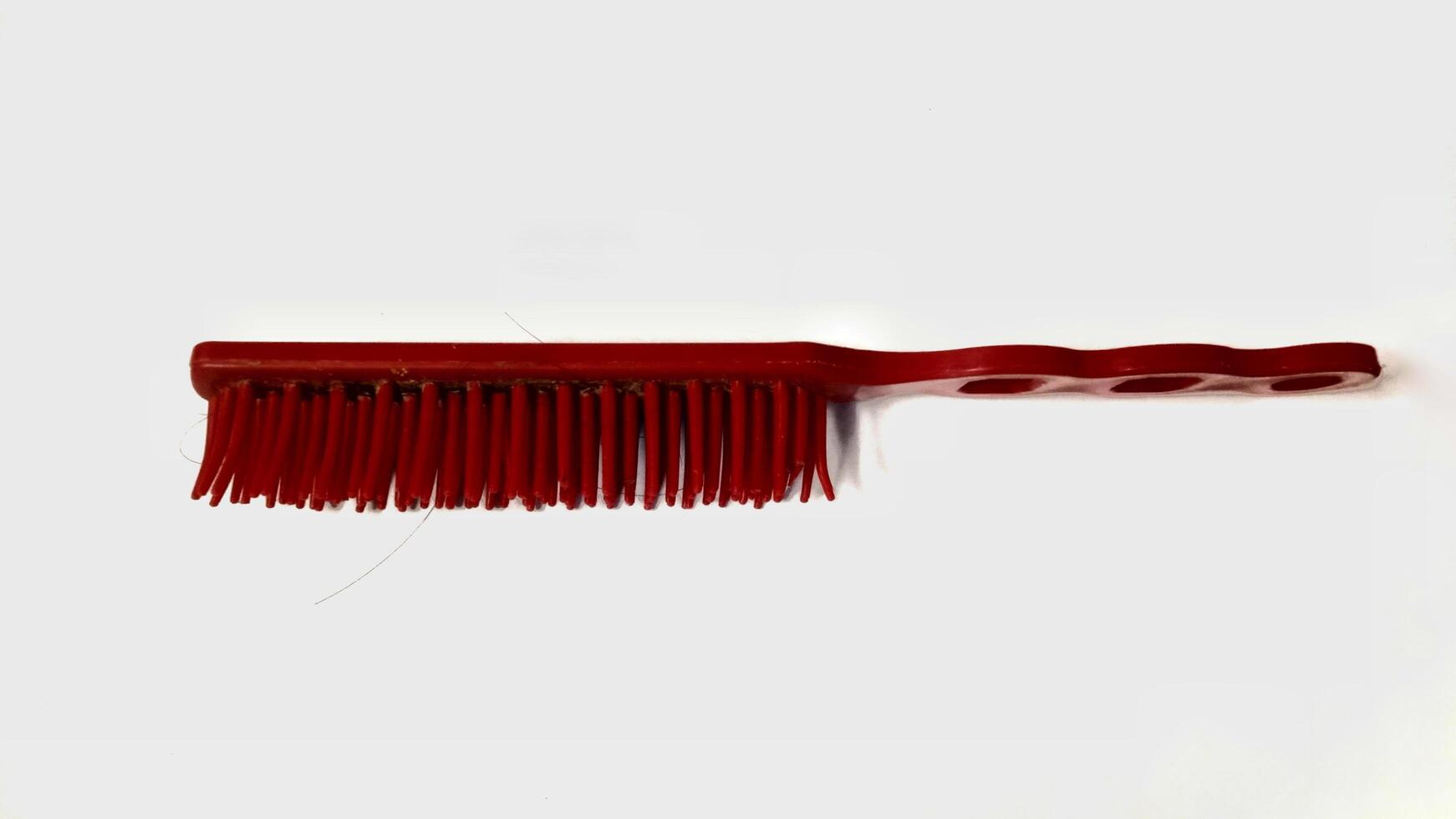 Close up of a red plastic cleaning brush with bristles, isolated on a white background. Cleaning supplies, household items. photo