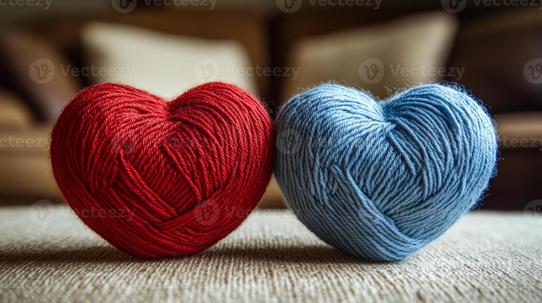 Two knit hearts made of yarn are sitting on a couch. The red heart is on the left and the blue heart is on the right photo