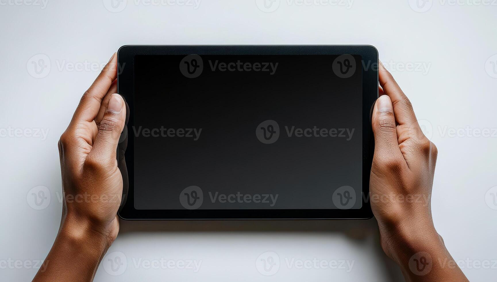 A person is holding a tablet with a black screen. The tablet is not turned on, and the person is holding it in their hands photo