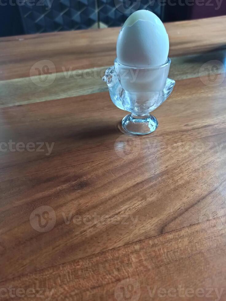Perfectly boiled egg served in a delicate glass holder on a smooth wooden table photo