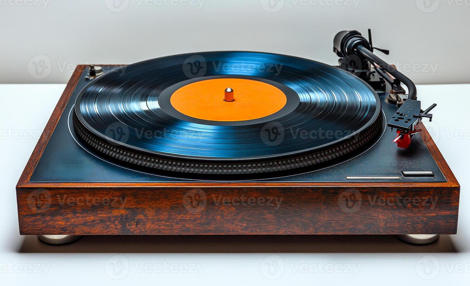 A record player with a black and orange record on it. The record player is on a wooden table photo