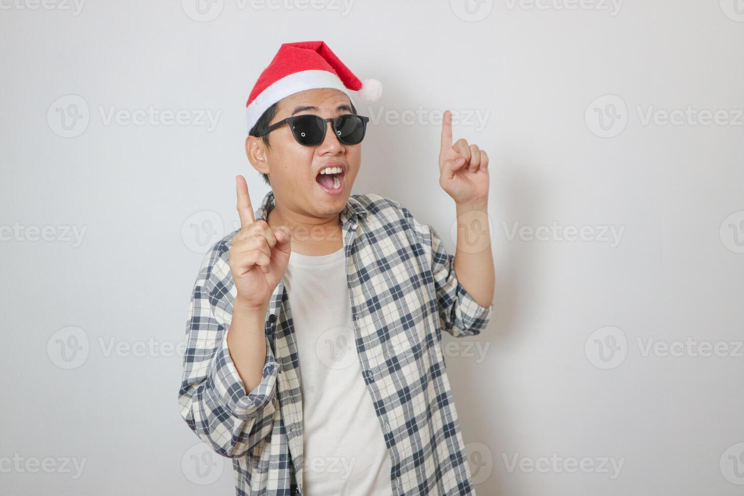 Portrait of an Asian man wearing a casual shirt and hat posing on a yellow background. photo