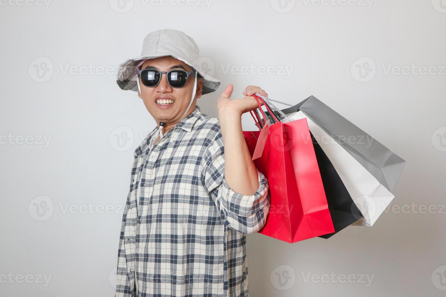 Asian man holding paper bag with fear and awe with mouth open for surprise. photo