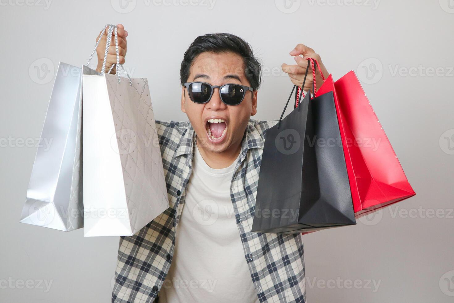 Asian man holding paper bag with fear and awe with mouth open for surprise, disbelief face. photo