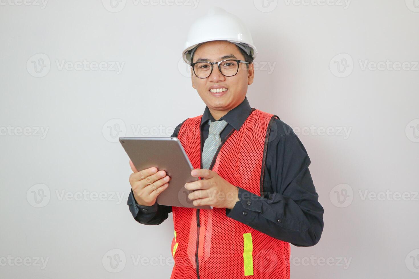 Confident asian engineer man Using tablet for checking and maintenance to inspection at modern home building construction. Architect working with white safety helmet in construction site photo