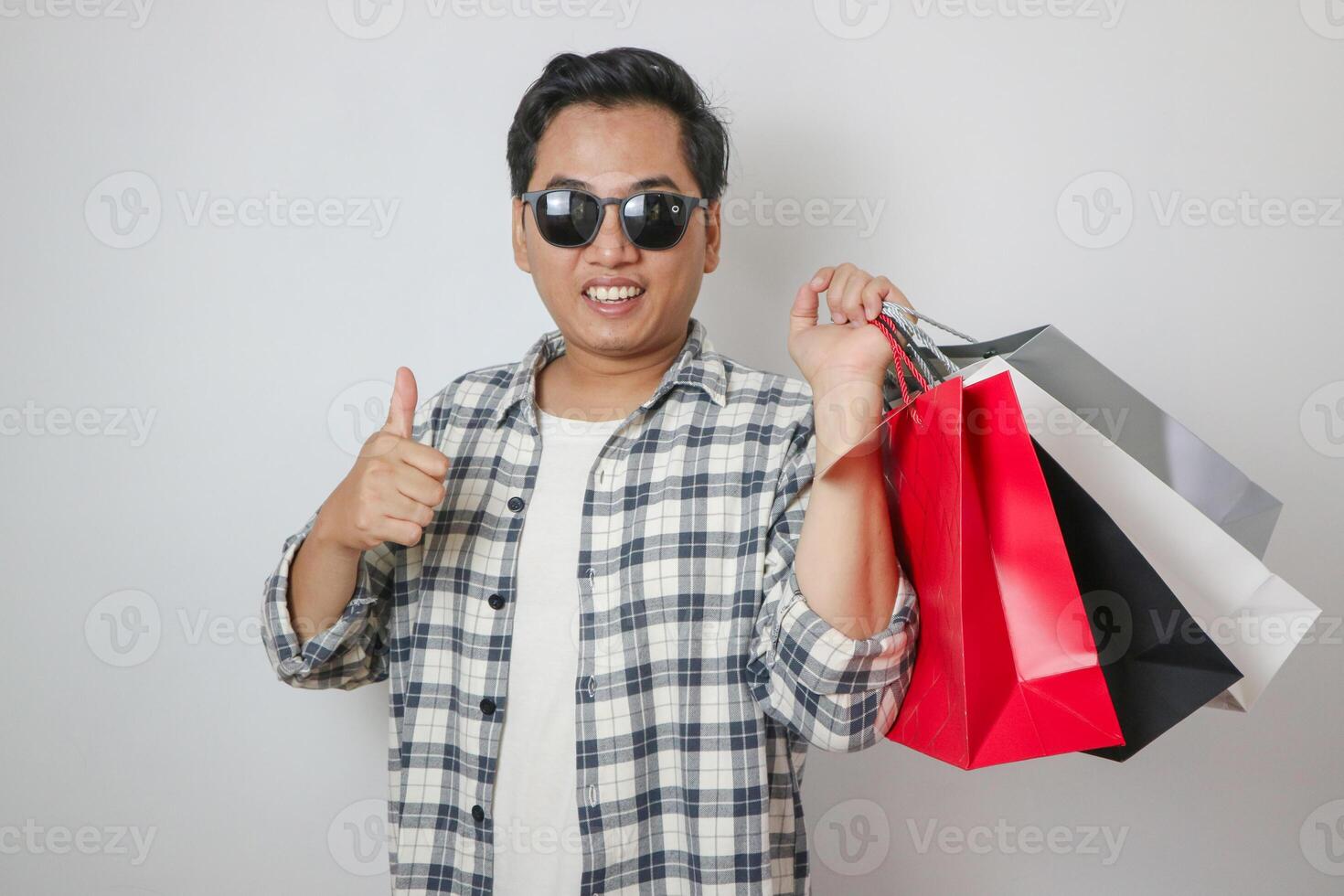 young attractive asian shopper man carrying shopping bag isolated on blue background. photo