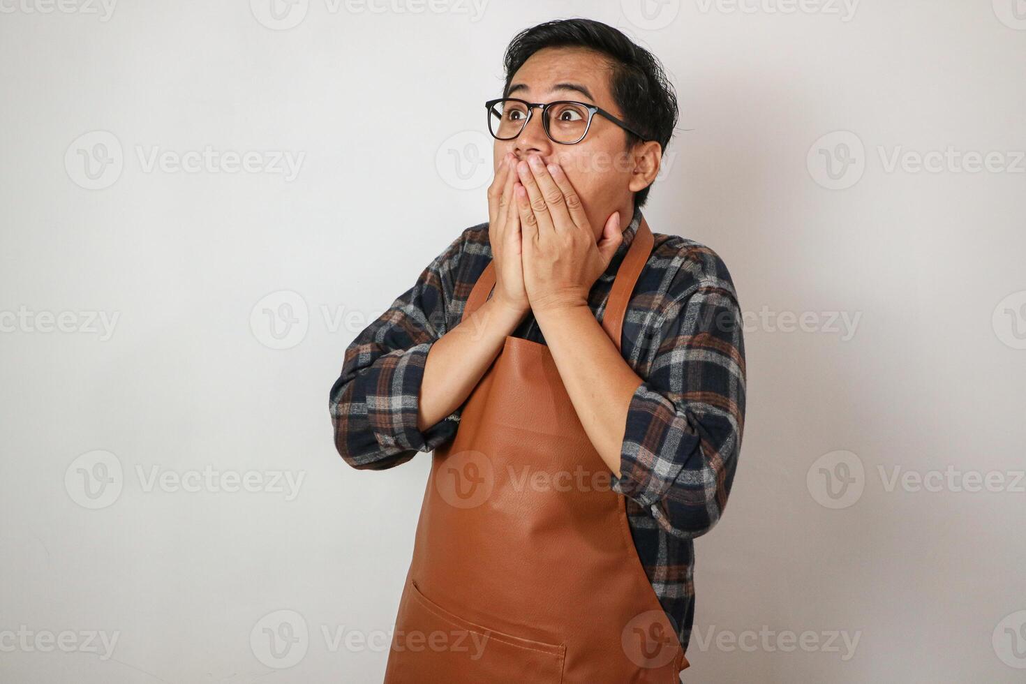 Asian man wearing apron surprised eating with restaurant concept photo