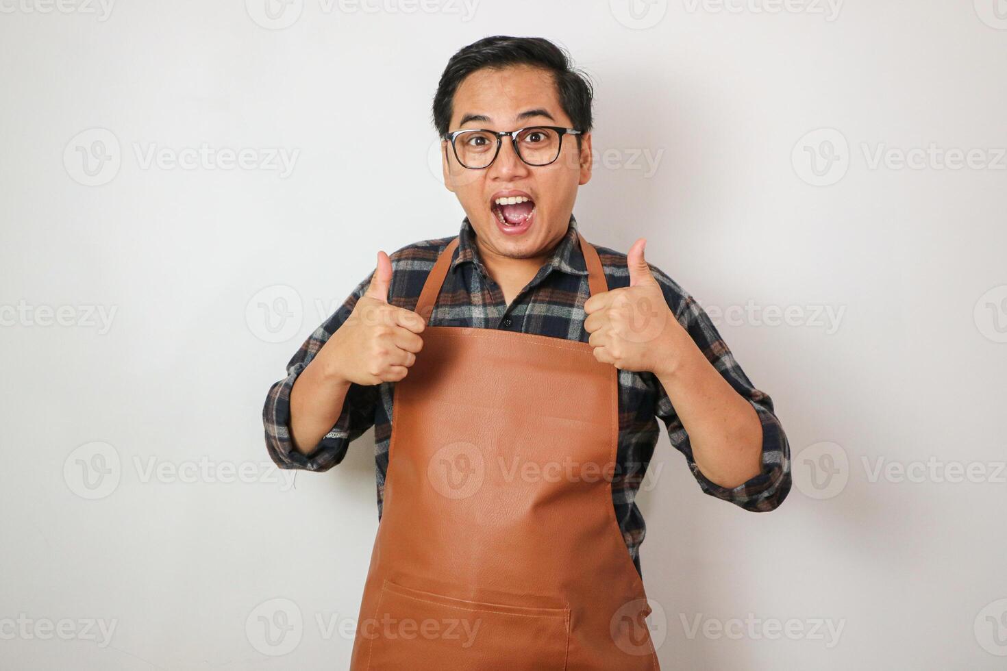 Asian man wearing apron holding thumbs up gesture with both hands photo