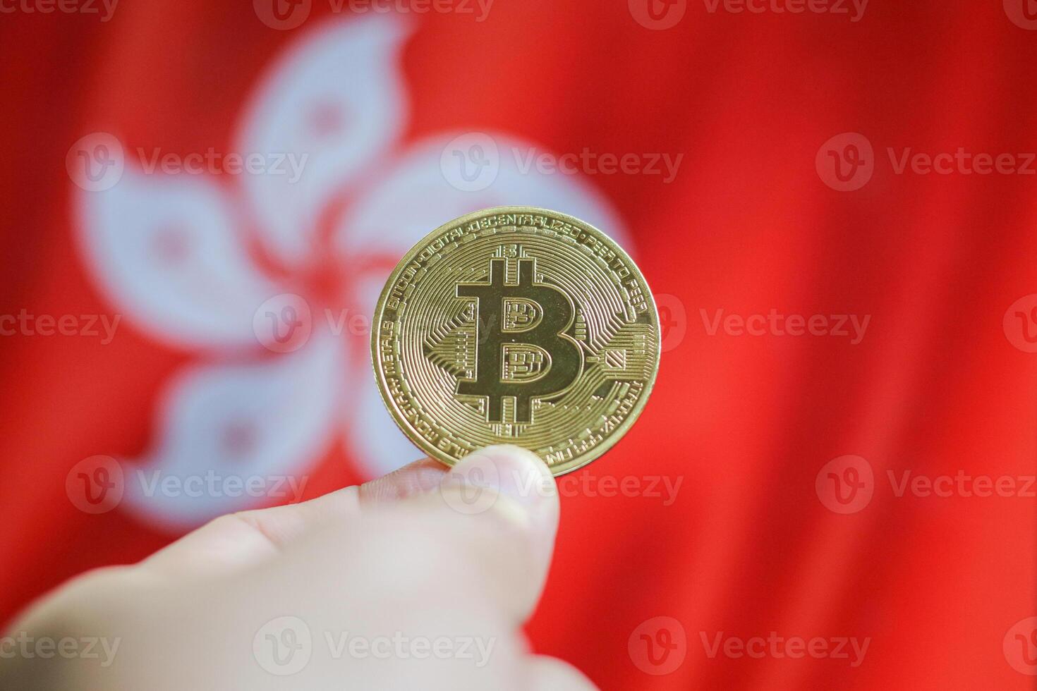 Hand of a man with a gold bitcone Cryptocurrency Digital bit of coins in a hand on a background of the flag of Hong Kong. photo