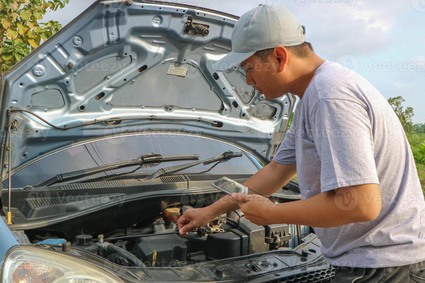 Asian automobile mechanic repairman wearing uniform and protection glove repairing a car engine automotive workshop, car service and maintenance, Repair service. photo