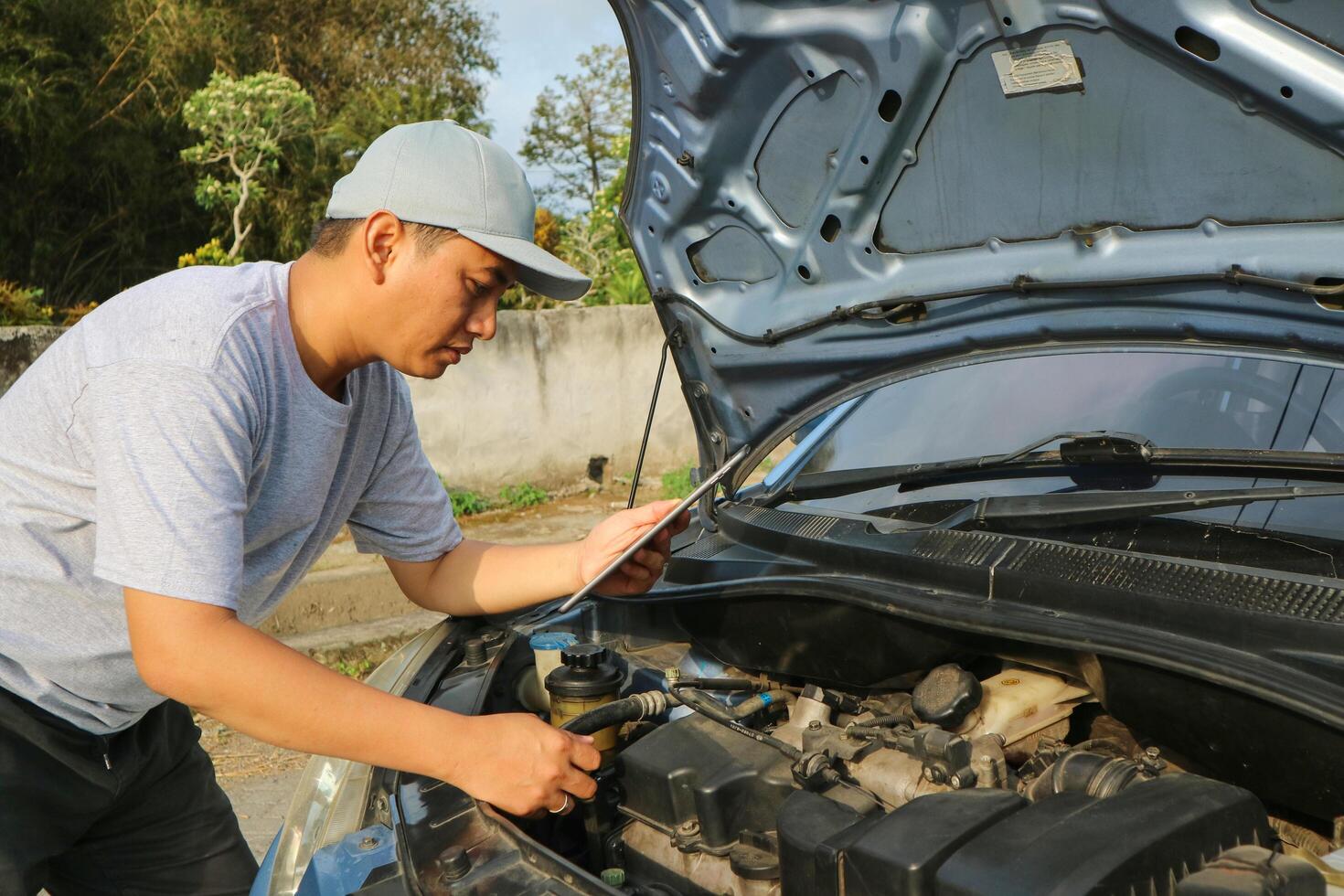 Professional car mechanic maintenance vehicle. The mechanic opens the front of the car. Checking the broken engine. Check the damage as listed. Repair car outside service. photo